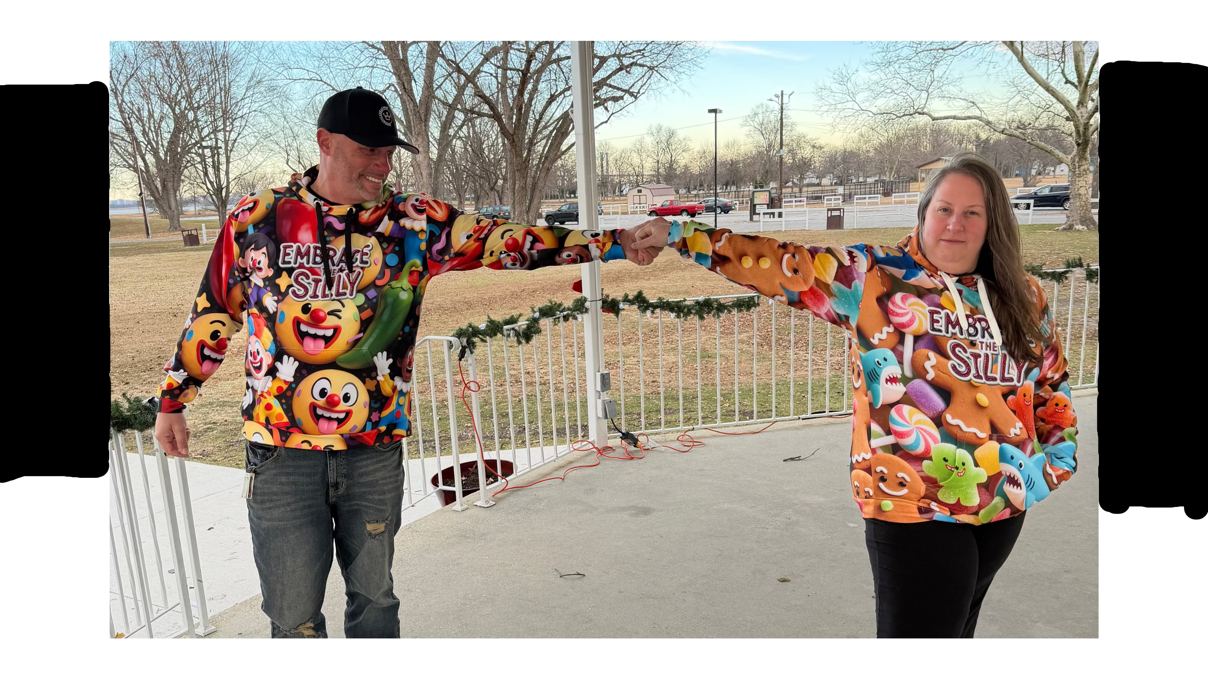 Two people wearing colorful sweatshirts with various designs outdoors.